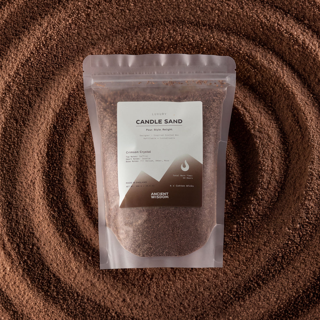 Fragranced candle sand in a glass vessel with a lit cotton wick