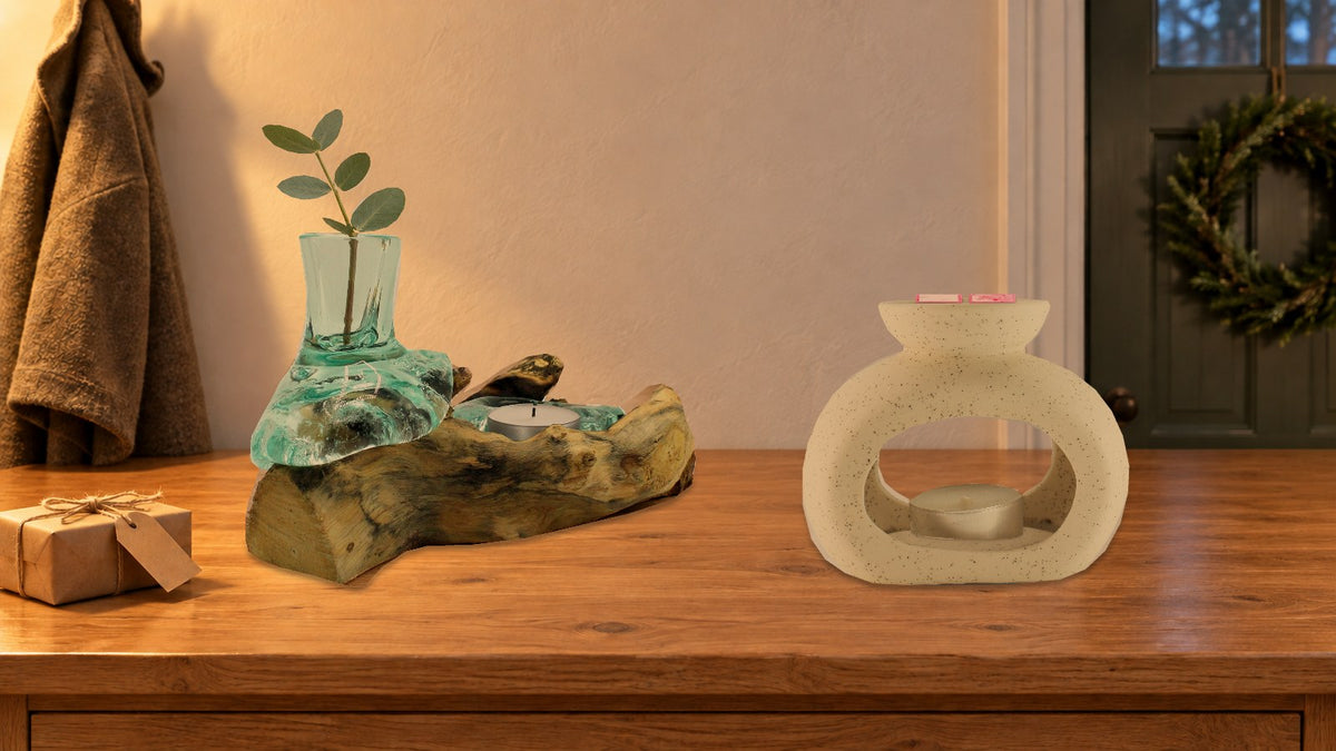 Glass vase and tealight holder on wood with a eucalyptus sprig and a speckled pebble wax burner with pink wax melts on a hallway table at Christmas, beside a kraft-wrapped present