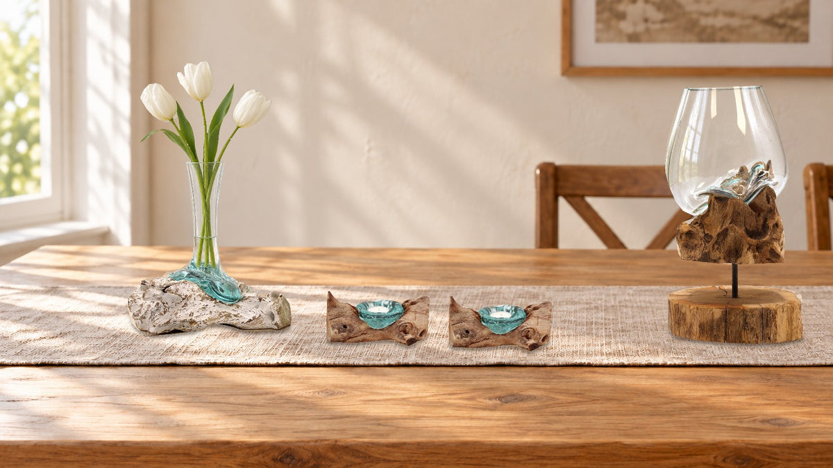 Oak dining table with a linen runner: a whitewashed wood vase of white tulips at one end, two glass tealight holders on wood in the middle and a glass bowl on a wooden stand at the far end