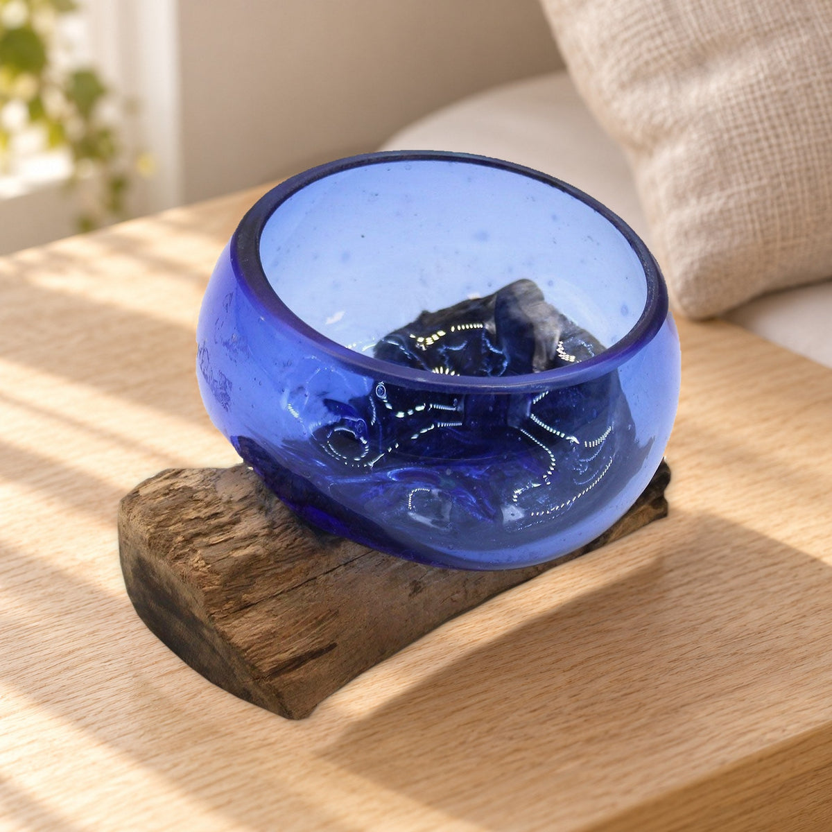 Mini cobalt blue molten glass bowl on wood, on a pale bedside table beside a linen pillow