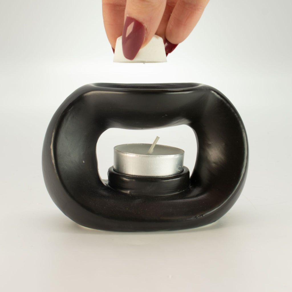 Placing a wax melt cube in the dish of the matt black pebble wax burner, with a tealight inside