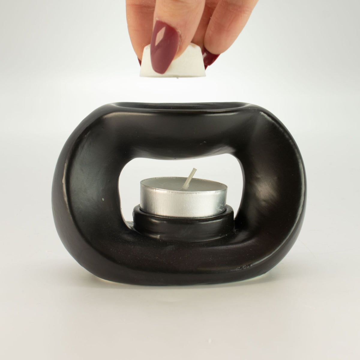 Placing a wax melt cube in the dish of the matt black pebble wax burner, with a tealight inside