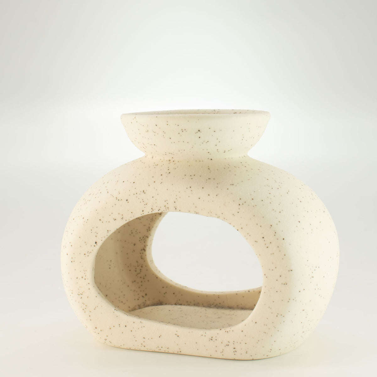 Pebble wax burner in speckled off-white ceramic, seen from an angle