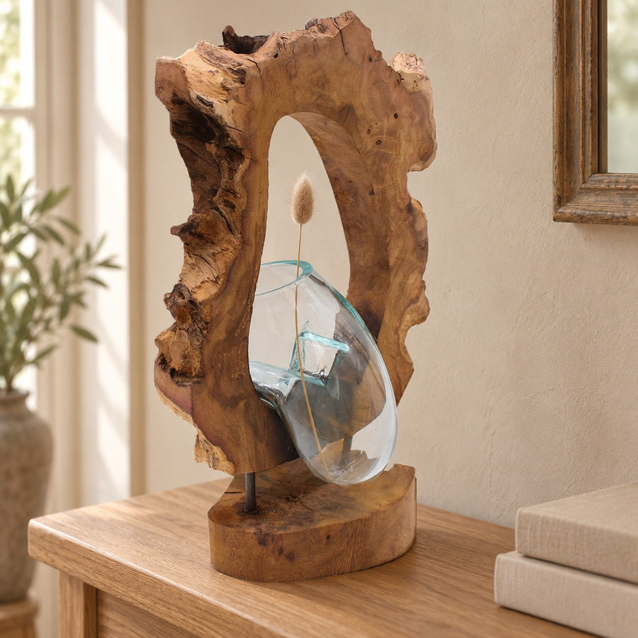 Hanging molten glass vase on wood holding one dried bunny-tail grass stem, on an oak hall console