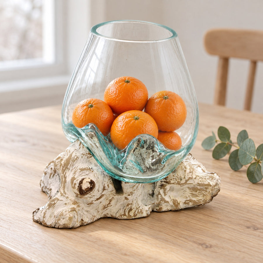 Large molten glass bowl on whitewashed wood holding whole clementines, on a pale oak dining table