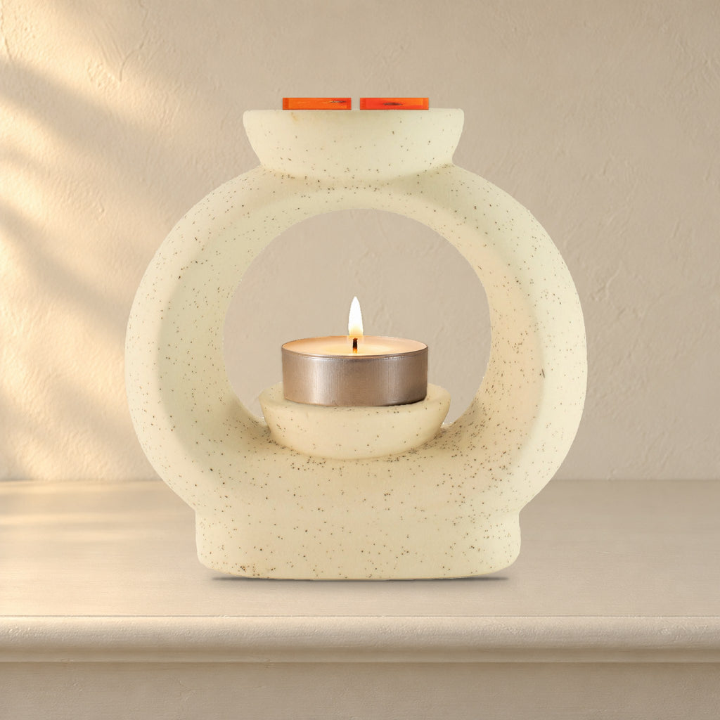 Large speckled off-white pebble wax burner with a lit tealight and Carnelian Fire wax melt squares, on a painted mantelpiece