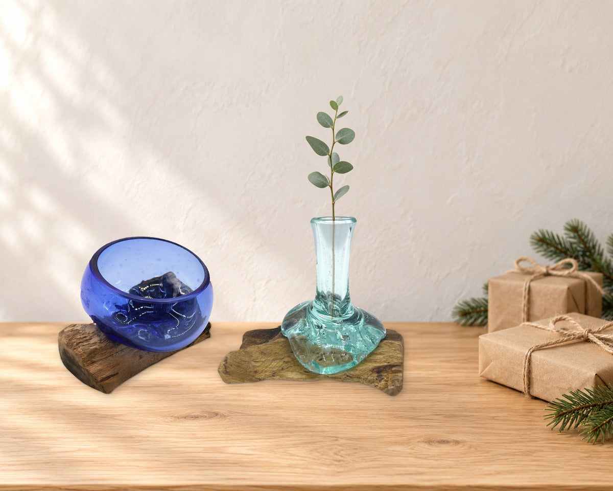 Mini cobalt blue molten glass bowl and small flower vase with a eucalyptus sprig, beside kraft-wrapped gifts on an oak sideboard