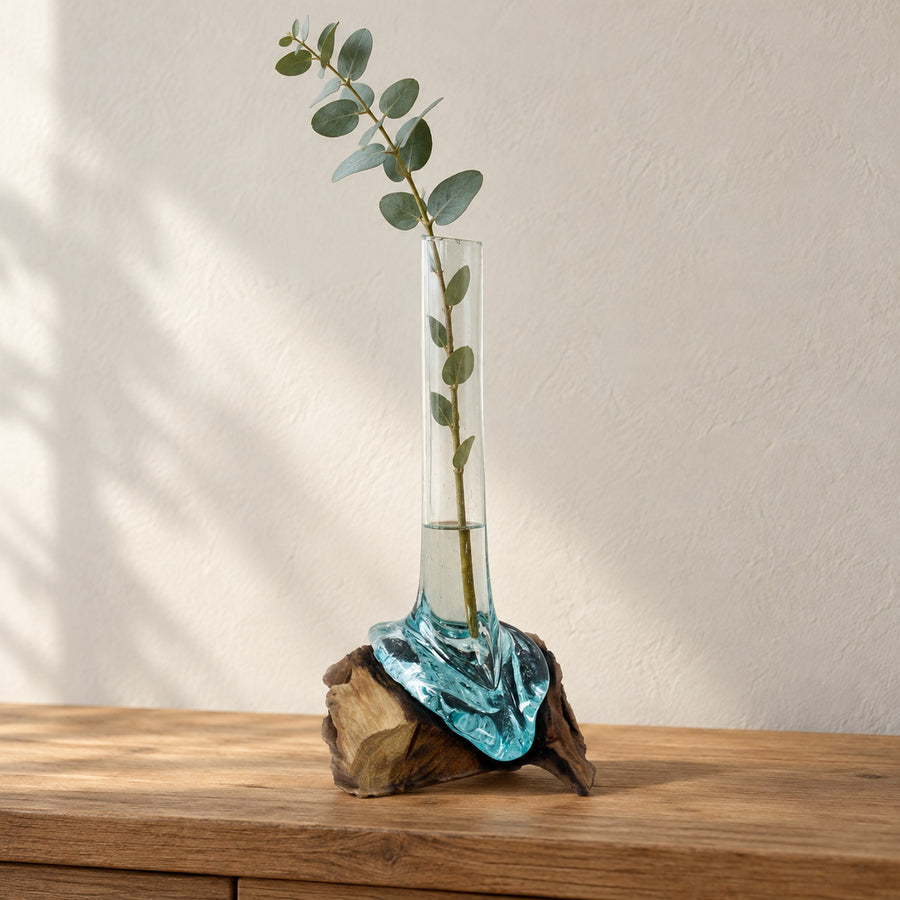 Tall molten glass vase on wood holding a eucalyptus branch, on an oak console